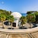 A domed building surrounded by palm trees and a circular decorative courtyard, overlooking the sea